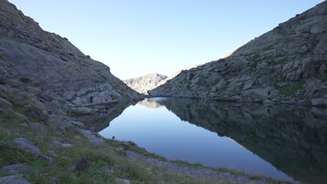 un hombre caminando solo en las montañas junto al lago, caminando hacia la cámara