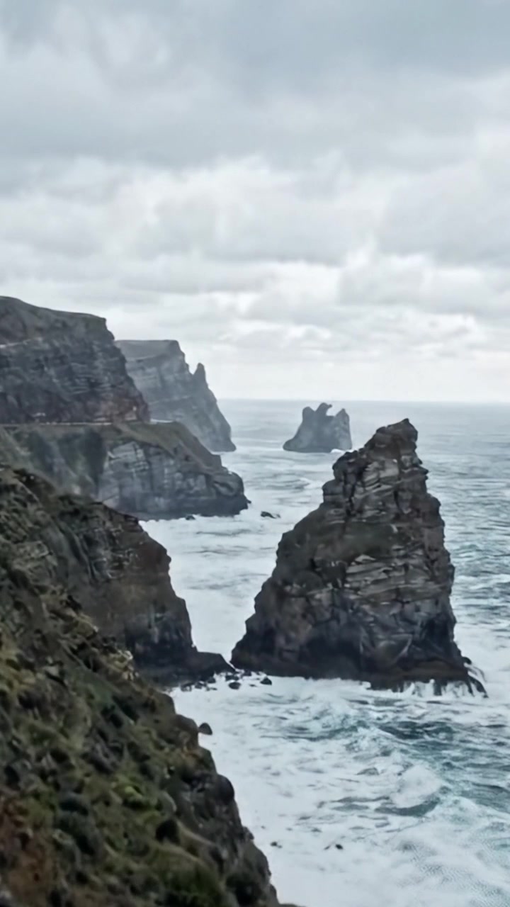 A Breathtaking Coastal Landscape with Dramatic Cliffs and Rocky Formations Overlooking a Choppy Ocean Under a Cloudy Sky