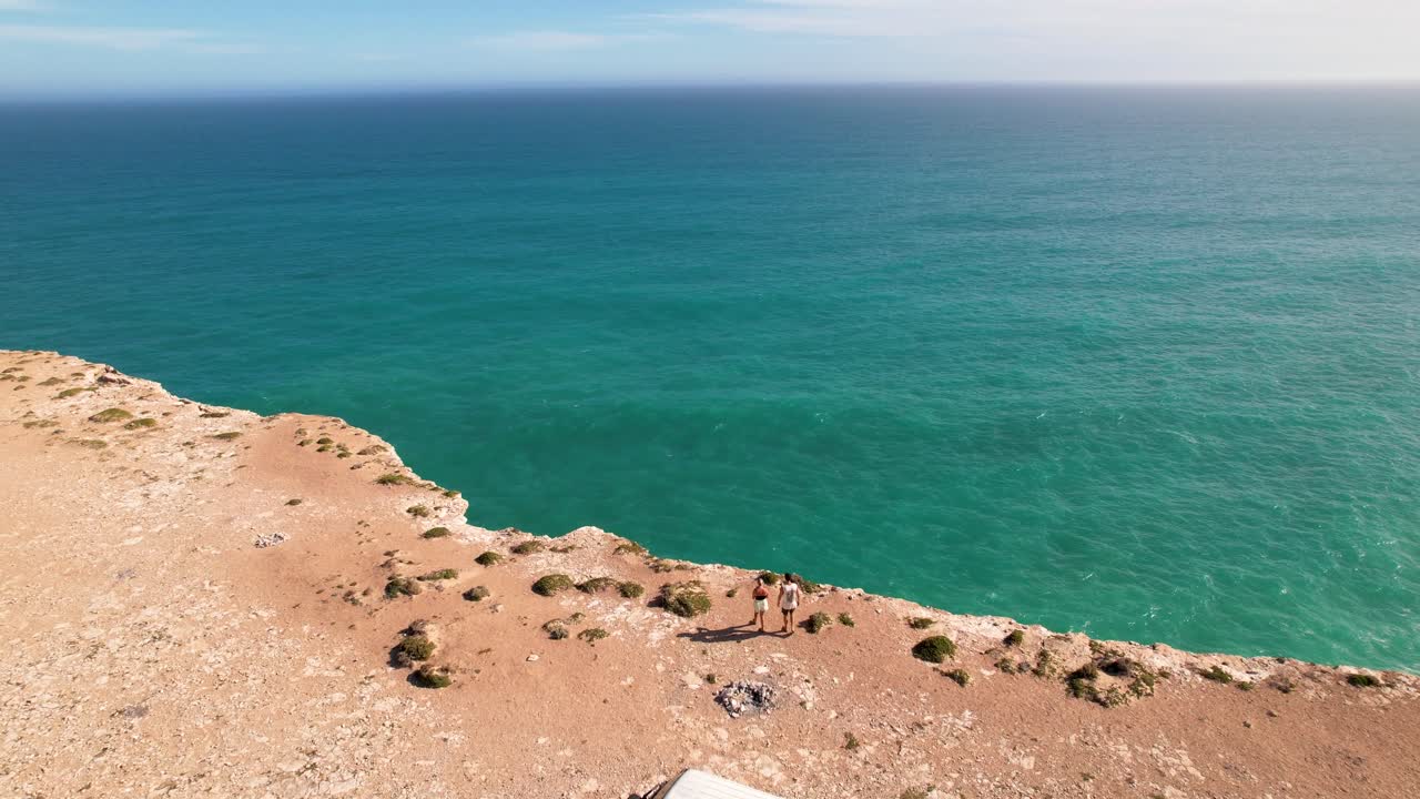 vista de un avión no tripulado de una pareja caminando hacia el borde de un acantilado