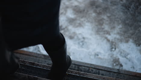 low view yellow bus halted at stop with open door, passengers stepping inside from wet snowy pavement, interior framing window and steps, urban transit moment during cold morning commute