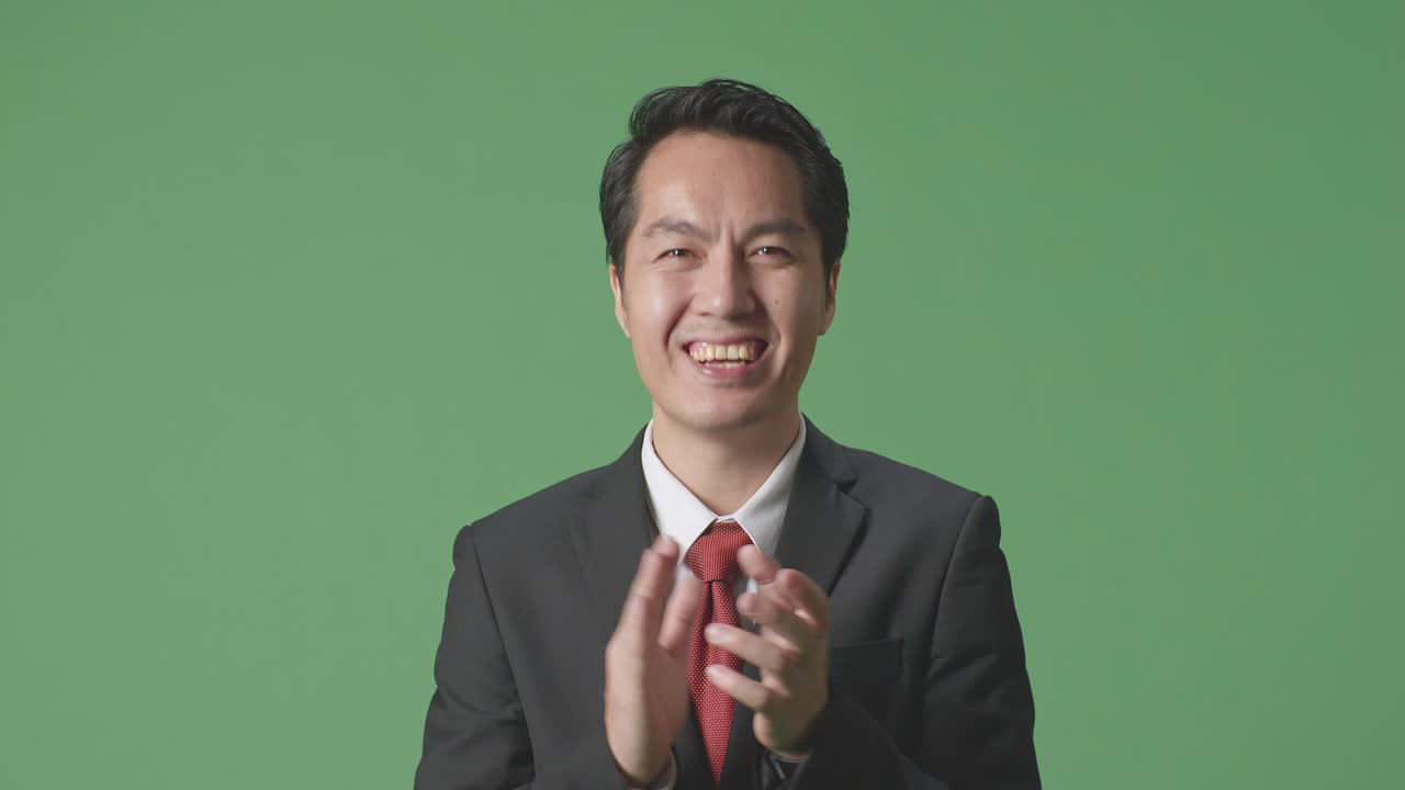 아시아 사업가 한 명 이 스튜디오 의 녹색 스크린 에서 인상적 인 손 을 박수 를 치고 있다