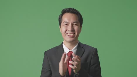 아시아 사업가 한 명 이 스튜디오 의 녹색 스크린 에서 인상적 인 손 을 박수 를 치고 있다