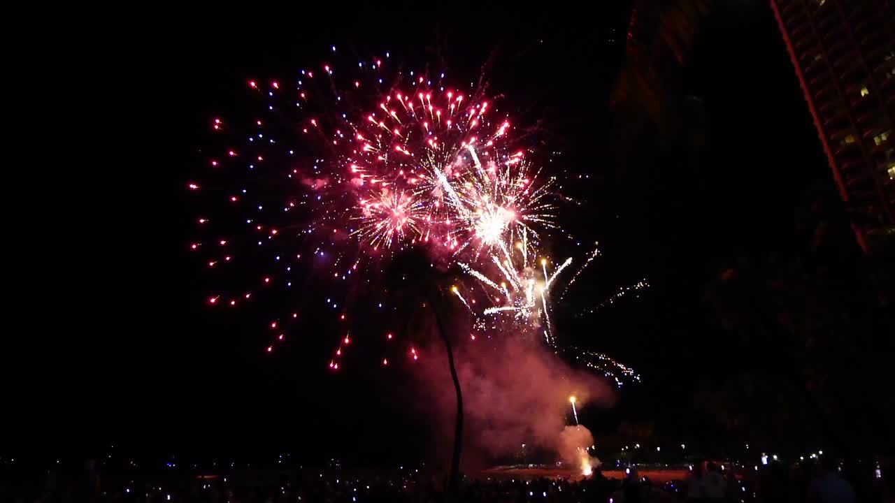 multitudes de personas viendo un colorido espectáculo de fuegos artificiales en la playa de waikiki, honolulu, oahu, hawai