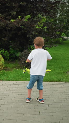 un niño pequeño gira enérgicamente un scooter en sentido antihorario en un camino entrelazado en un parque