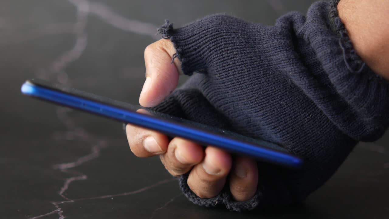 mano con guantes rasgados usando un teléfono inteligente