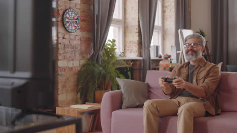 middle age man playing console game at home