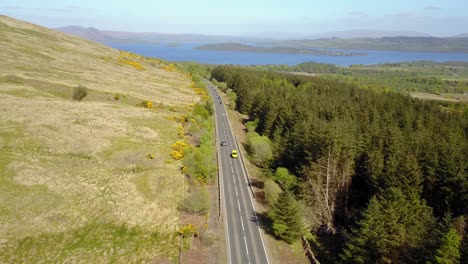 aerial forward over scottish road and lomond lake in background, lowlands in scotland