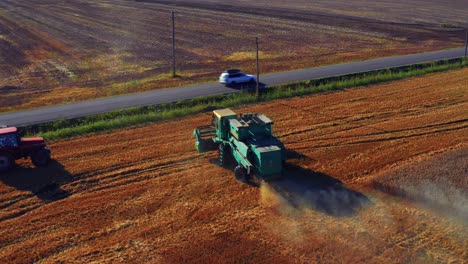 combine tractor harvesting wheat in a field in lithuania - drone shot