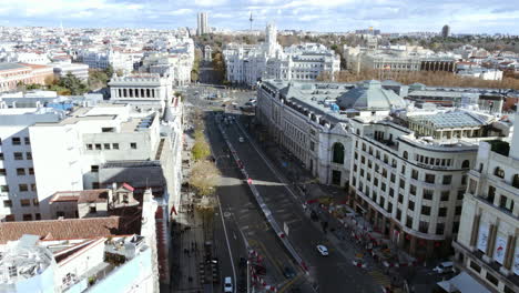flying over the dome of metropolis building and copter moving along calle de alcala leading to cibeles square with town hall. madrid aerial cityscape, spain