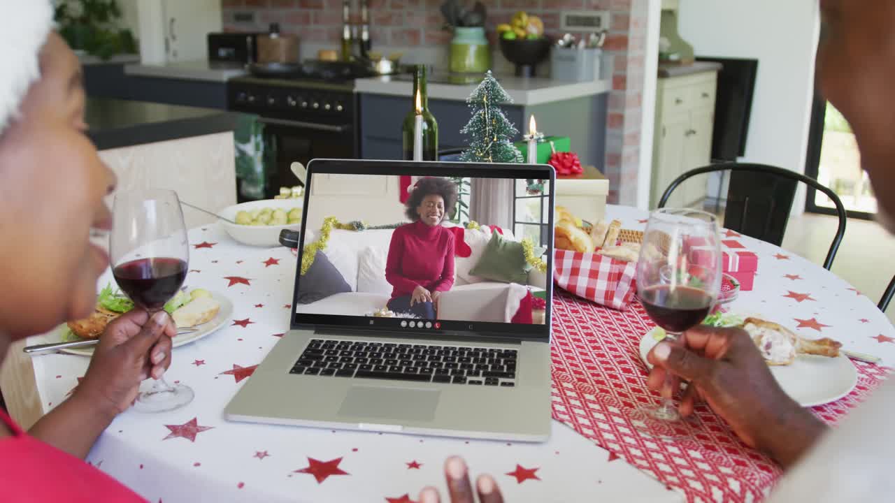 크리스마스 비디오 통화를 위해 노트북을 사용하는 미소 짓는 아프리카계 미국인 부부