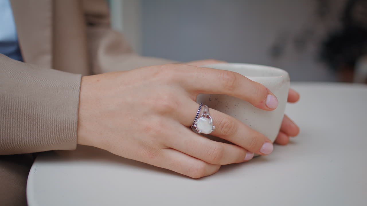 카페에서 뜨거운 음료를 가진 컵을 들고 있는 클로즈업 소녀의 손