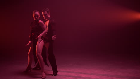 full length professional couple dancing indoors. dancers moving sensually.