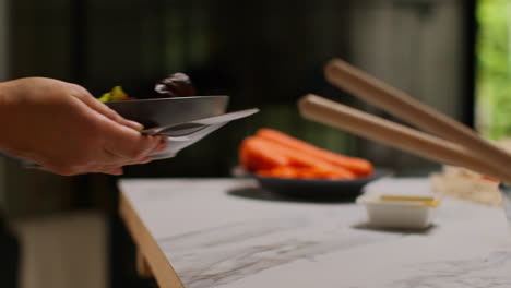 close up de una mujer en casa en la cocina preparando una comida saludable vegetariana o vegana comiendo un plato de hojas de ensalada con semillas y aderezo