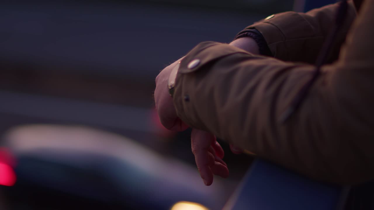 близкий кадр рук человека, хватающего за перила железного моста, с проезжающими машинами на размытом фоне. кадр захватывает созерцательный и кинематографический момент одиночества.