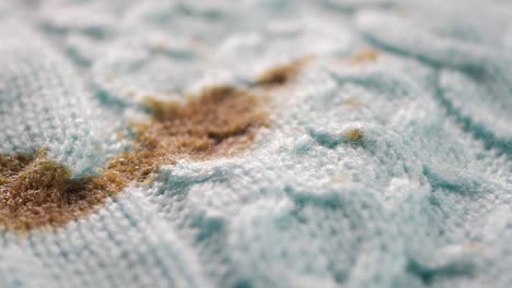 close-up of a light blue knitted fabric with brown stains