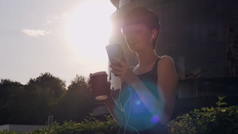 dama desplazándose en el teléfono inteligente y escuchar música en la calle.