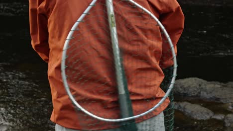 close-up shot of a fisherman casting with a green net on his back