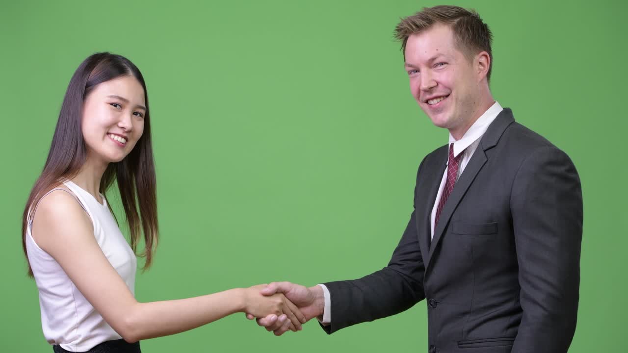 Multi-ethnic business couple shaking hands together