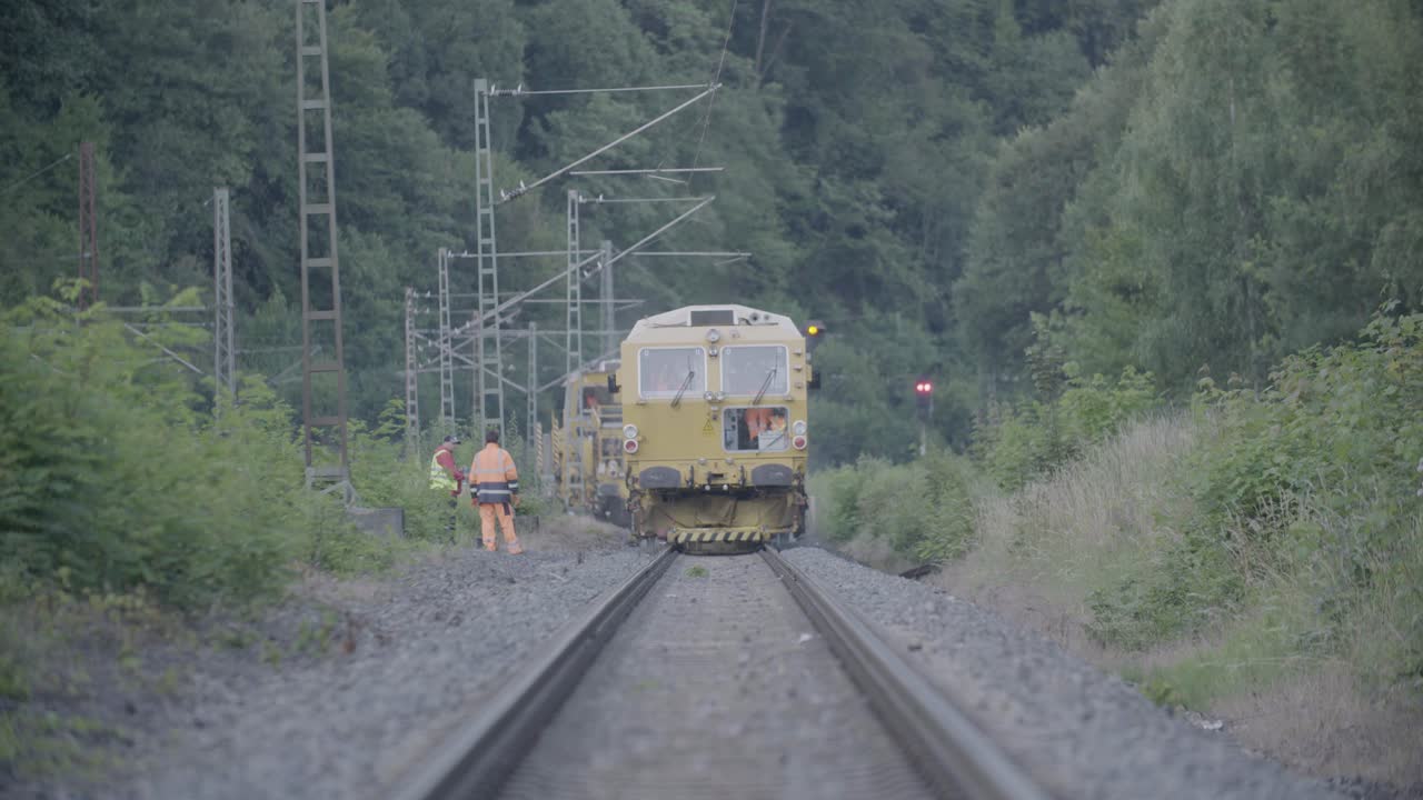 Railway workers with a train on tracks in a forested area