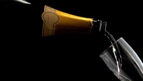 Animation-of-paper-burning-over-champagne-pouring-into-glass-on-black-background