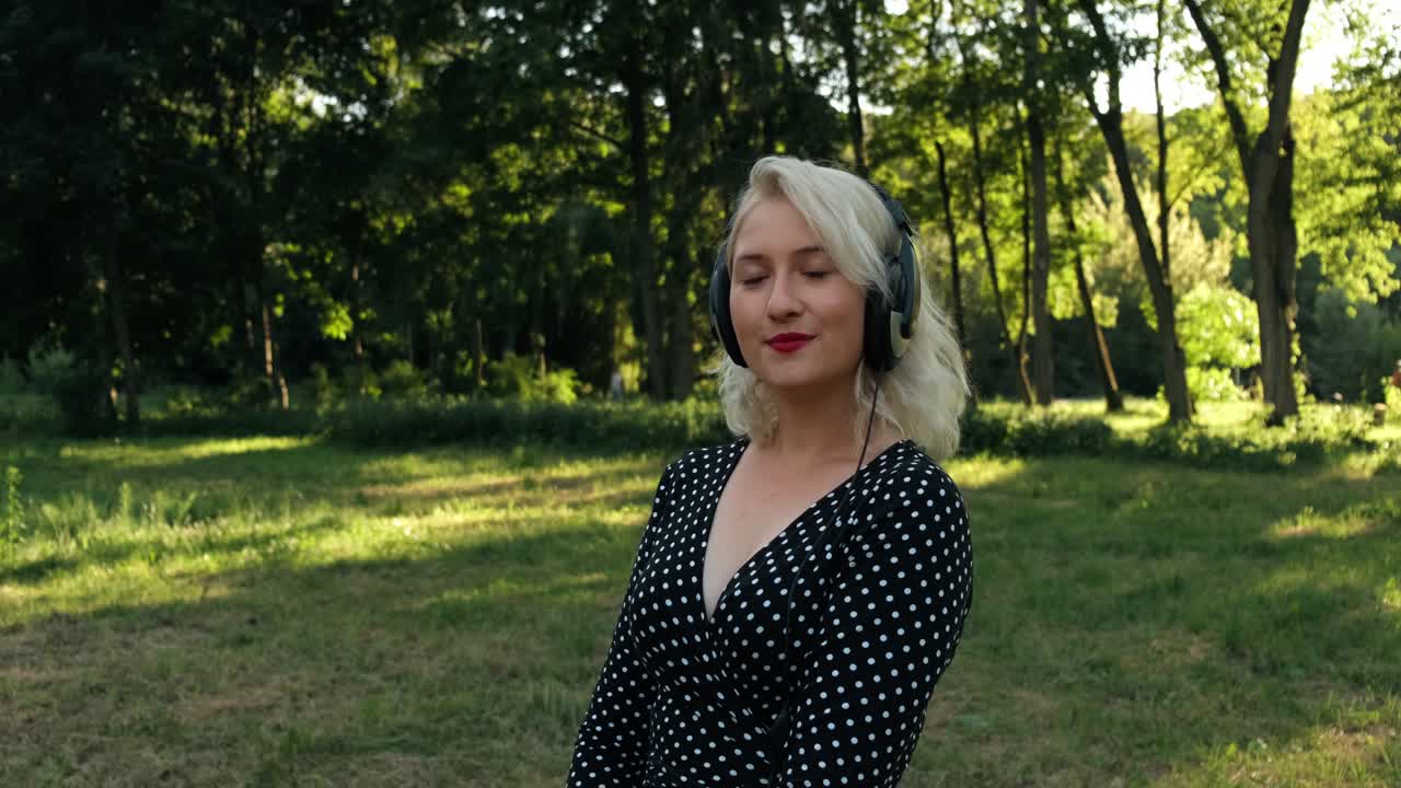 Glad og positiv blondine lytter til musik og smiler.