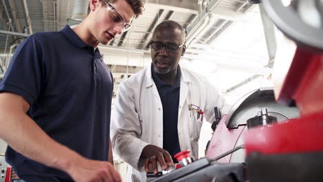 engineer teaching apprentice how to use machine in factory