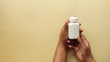 a hand holding a white bottle of pills