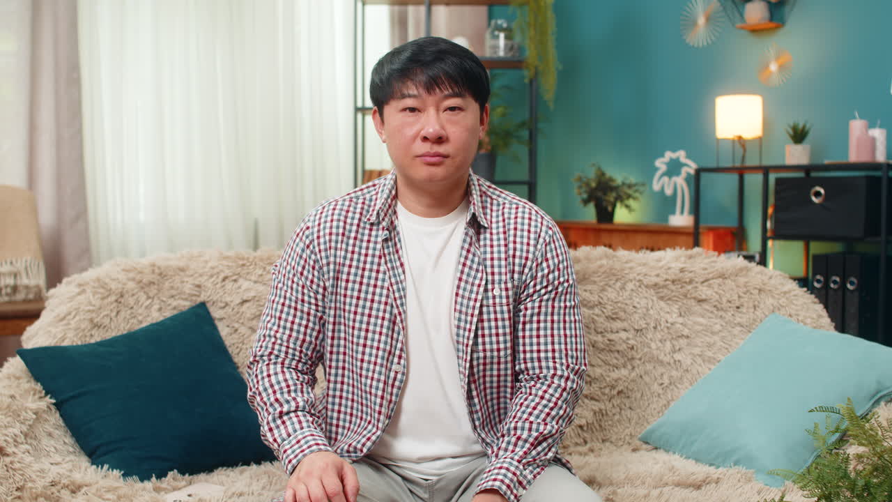 Asian man showing thumbs down unhappy dislike expression signaling strong negative disagreement