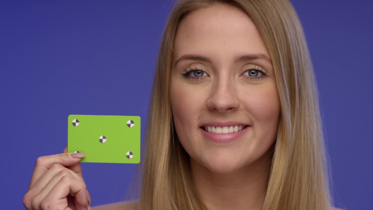 retrato cercano de una mujer sosteniendo una tarjeta en blanco y dando una sonrisa impresionante a la cámara