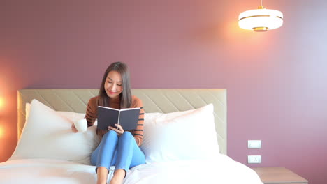 hermosa mujer leyendo un libro de novela romántica en el dormitorio, vista estática