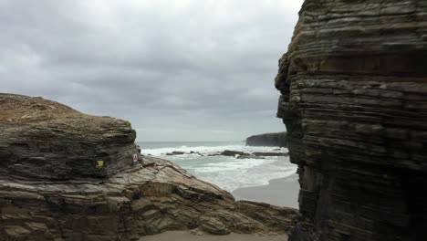 Huge-Rock-Formations-Aerial-Reveal-Wild-Coastal-Sea-at-Beach-of-the-Cathedrals,-Spain