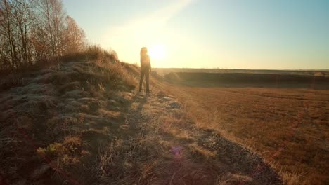 woman standing on a hill at sunrise
