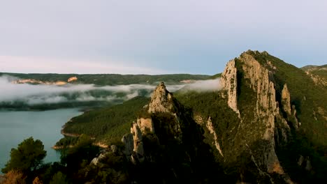 Wolken,-Die-Bergketten-Bedecken,-Wasserfluss-Zu-Fuß-Von-Bergspanien,-Drohnenblick-Auf-Bergketten