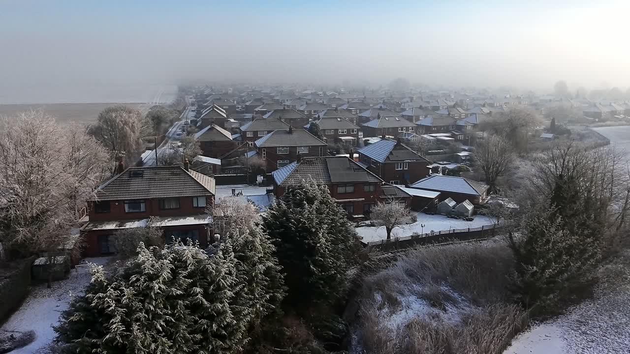 Chilly morning mist covering British small town neighbourhood houses and farmland aerial view