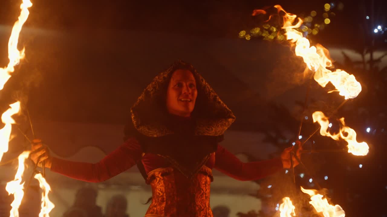 Performance dramática de fogo em câmera lenta à noite, com uma atmosfera mística de festival.