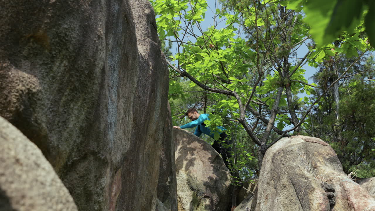 Hiker guy climbing a mountain in the forest bottom view