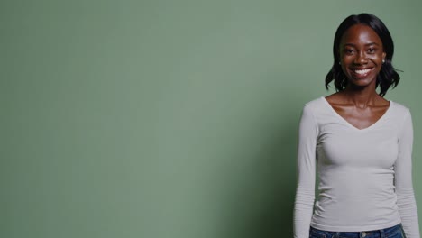 cheerful african american model standing in studio, smiling confidently while posing against green background, radiating positive energy and modern style