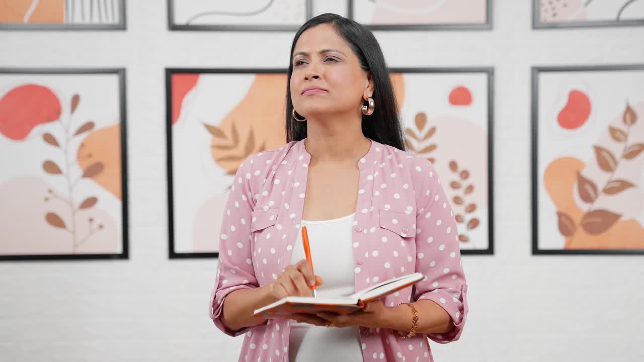 mujer india pensativa escribiendo un libro