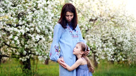 mother and little daughter are hugging in nature