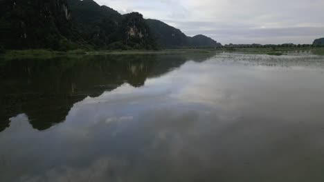 Impresionante-Sobrevuelo-Del-Lago-Asiático-Perfectamente-Inmóvil-Con-El-Reflejo-De-Las-Montañas-Y-El-Cielo-En-El-Agua