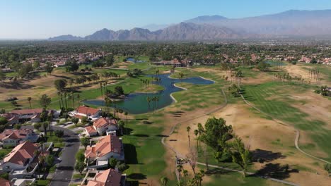 drone se eleva sobre el campo de golf y el lago en palm springs, california, estados unidos, vista panorámica de las casas