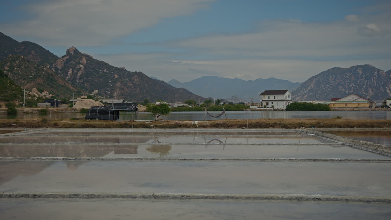 Salt Evaporation Ponds with Mountains and Village in the Background