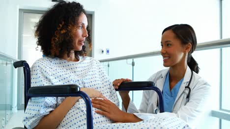 Doctor-interacting-with-pregnant-woman-in-corridor