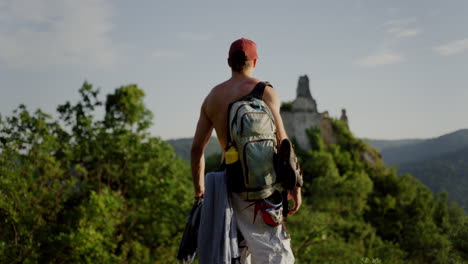 hiker-looking-over-the-valley,-seeing-durnstein-castle,-burgruine,-green-mountain-Austria-horizon,-athletic-outdoor-hiking-man-on-a-trekking-trail-walk-in-nature