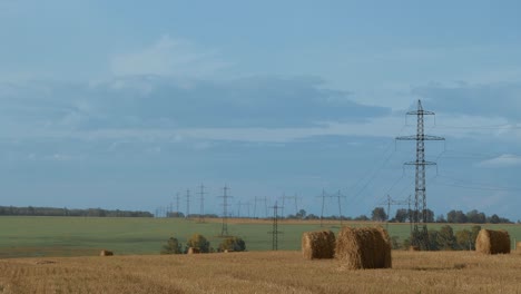balas redondas de heno seco en el campo del agricultor con líneas eléctricas. lapso de tiempo del paisaje rural con nubes corrientes