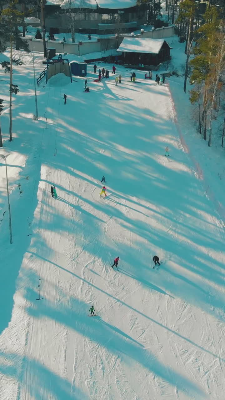 people in winter dressing speed along mountain ski resort track surrounded by pine trees vertical aerial view