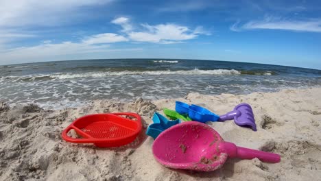 plastic toys on sandy beach. ocean waves in background.