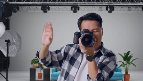 un primer plano de un fotógrafo asiático diciéndole al modelo que se mueva a la izquierda y a la derecha mientras toma fotos con la cámara en el estudio