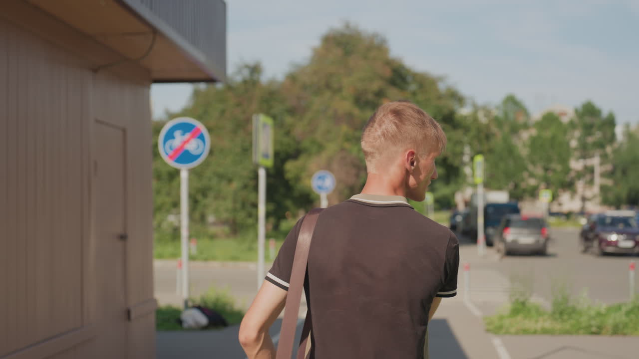 Man Pausing At Parking Lot Entrance, Facing Street Signs And Parked Cars Brief Hesitation, Shoulder Bag, Sunlit Summer Scene, Urban Signage And Commuter Tension Suggesting Uncertainty