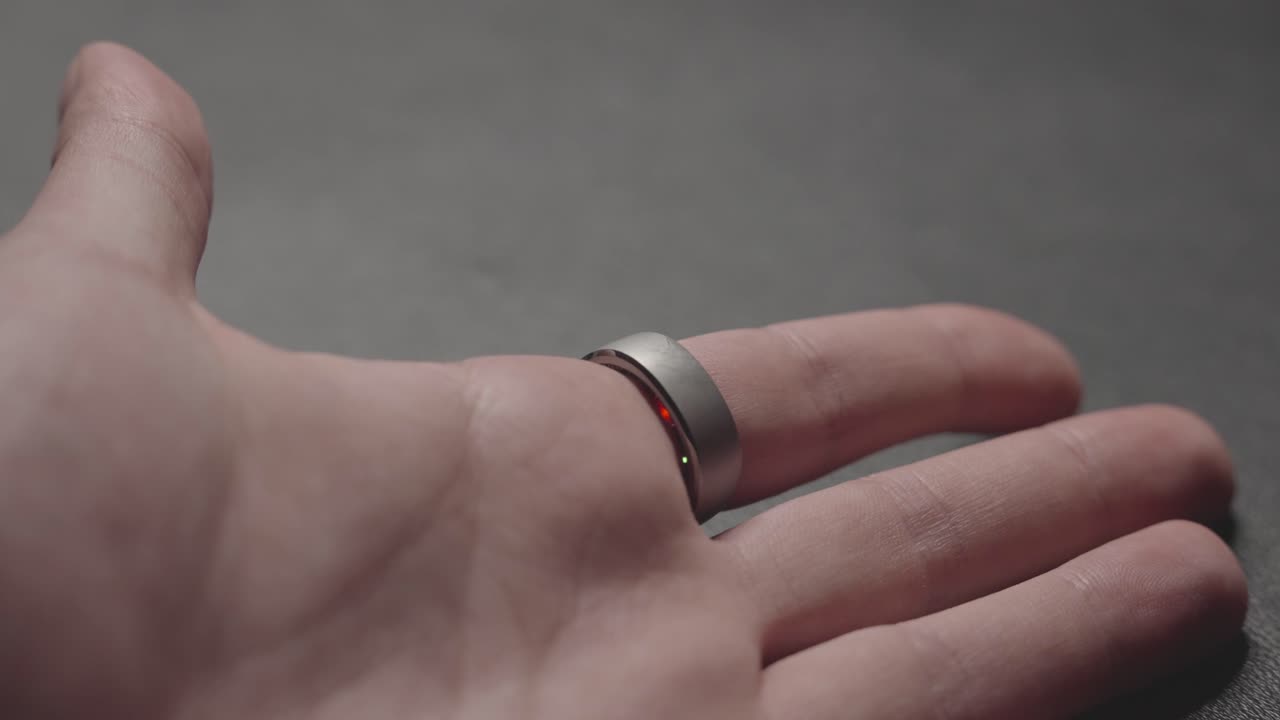 Smart ring glows softly as it tracks vital signs. Wrapped around a finger, it blinks with data signals, seamlessly blending technology with everyday wear.